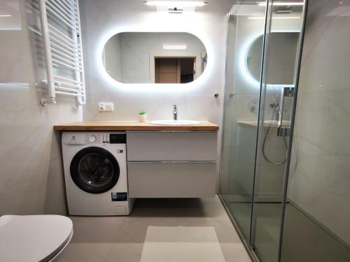 a bathroom with a washing machine and a sink at Apolonia apartamenty I - SPA in Dziwnów