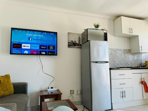 a kitchen with a refrigerator and a tv on the wall at Mila Lodge 2 in Cape Town