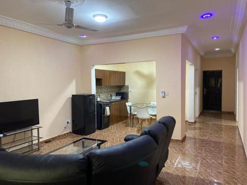 a living room with a black couch and a table at Saffy Guest House in Brikama