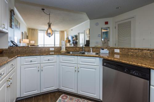 a kitchen with white cabinets and a sink at Beach Club - Doral 1503 - DIRECT BEACHFRONT, INCREDIBLE VIEWS, COZY DECOR, TONS OF AMENITIES! in Gulf Highlands