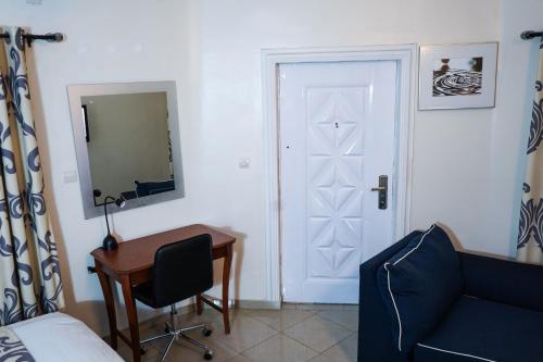 a bedroom with a bed and a desk and a door at EKA ELITE HOTEL in Lomé