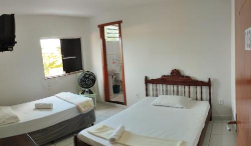 two beds in a room with a window at indaiá Pousada - Posto da Mata-BA in Pasto da Mata