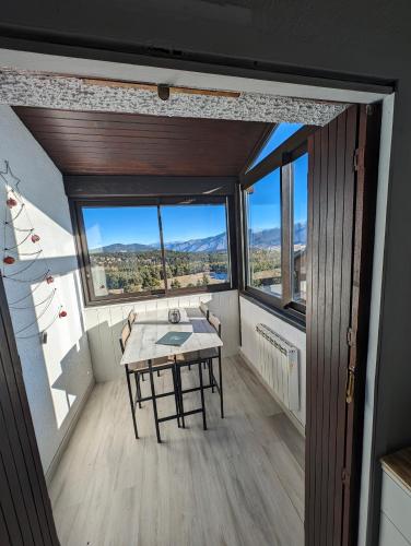 une pièce avec une table, des chaises et des fenêtres dans l'établissement Ski'libre, à Bolquère-Pyrénées 2000