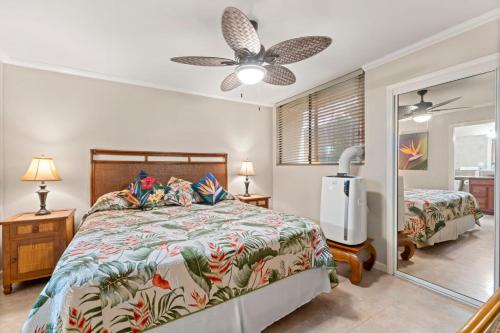 1 dormitorio con cama, ventilador y espejo en Kamaole Beach Club B107 BY Betterstay, en Kihei