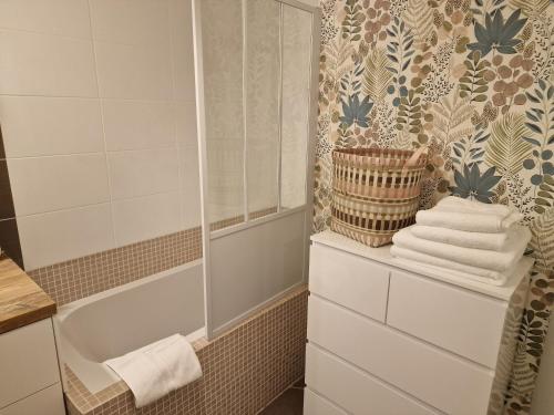 a bathroom with a shower and a tub and towels at Résidence neuve avec parking intérieur et balcon in Vienne