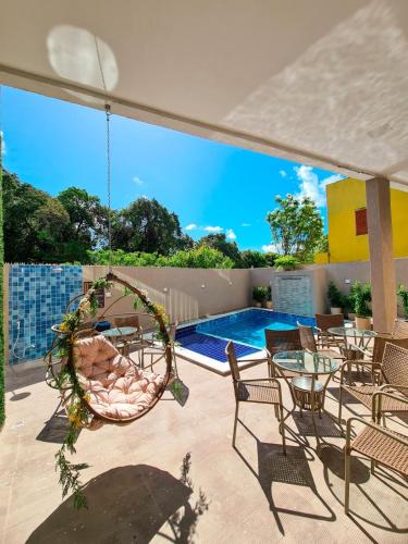 a patio with chairs and a swing and a pool at Sunset by AFT - PORTO DE GALINHAS in Porto De Galinhas
