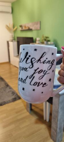 a person holding a coffee cup with writing on it at Finans1 in Ruma