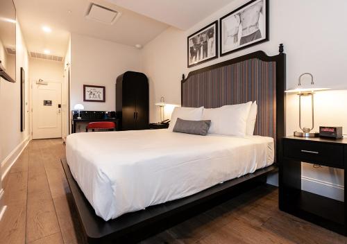 um quarto com uma grande cama branca e uma secretária em The Rubenstein Hotel em Nova Orleans