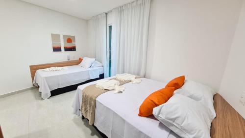 a bedroom with two beds with orange pillows on them at Sunset by AFT - PORTO DE GALINHAS in Porto De Galinhas