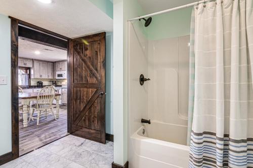 a bathroom with a wooden door and a tub at Serene Tell City Retreat Near Hiking and Skiing! in Tell City