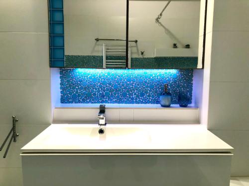 a bathroom with a sink with a blue accent wall at Apartmán v centre Žiliny s parkovaním in Žilina