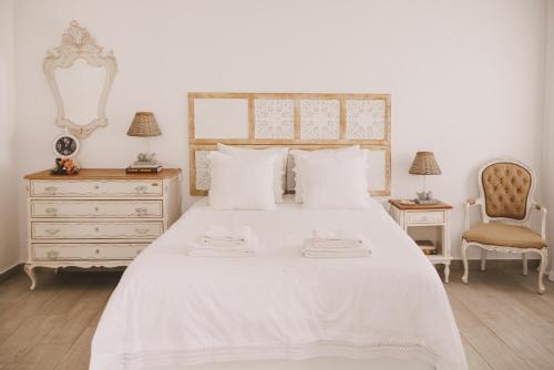 ein Schlafzimmer mit einem weißen Bett mit einer Kommode und einem Stuhl in der Unterkunft Casa Coração Alentejano- Casas com EnCanto in Reguengos de Monsaraz