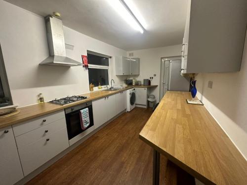 a kitchen with white cabinets and a wooden counter top at Large 3 bedroom house in Nottingham