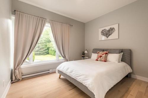 - une chambre avec un lit et une grande fenêtre dans l'établissement Modern Lake Champlain Villa with Spa, à Venise-en-Québec