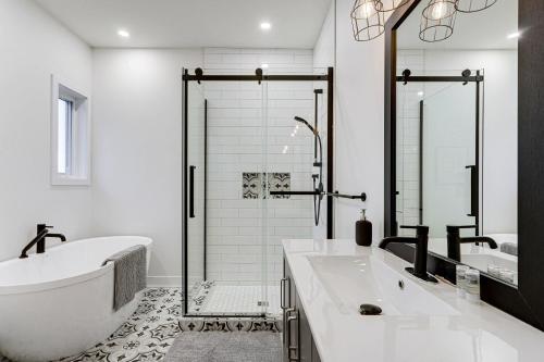 La salle de bains est pourvue de 2 lavabos, d'une baignoire et d'une douche. dans l'établissement Modern Lake Champlain Villa with Spa, à Venise-en-Québec