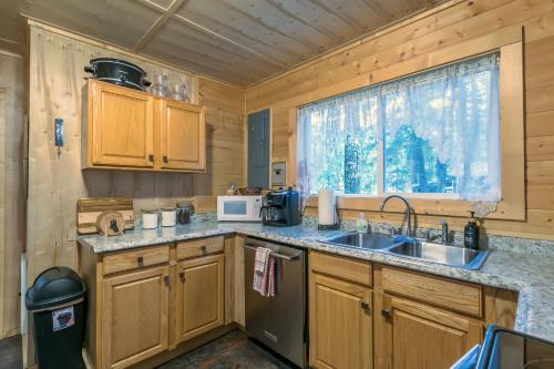 uma cozinha com armários de madeira, um lavatório e uma janela em The Yellow Cabin BY Betterstay em Packwood