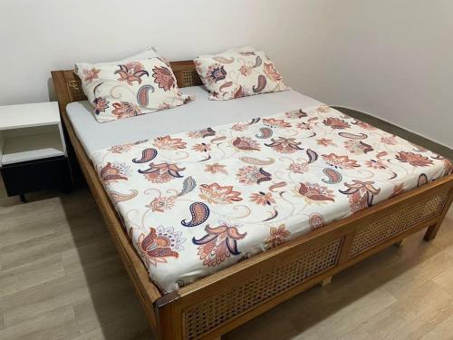 a bed with a floral blanket and pillows on it at Cozy 1 Bed Apartment East Legon in Bawaleshi