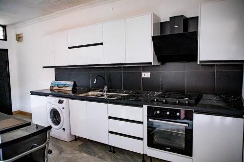 a kitchen with white cabinets and a sink and a dishwasher at Cozy 1 Bed Apartment East Legon in Bawaleshi