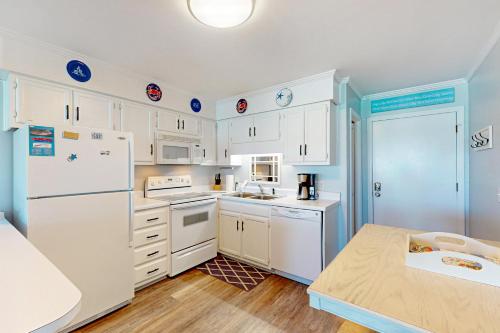a kitchen with white cabinets and a white refrigerator at Seaspray 320 in Atlantic Beach
