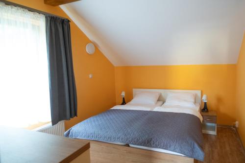 a bedroom with a bed with orange walls and a window at Apartamenty Sadowy in Wisła