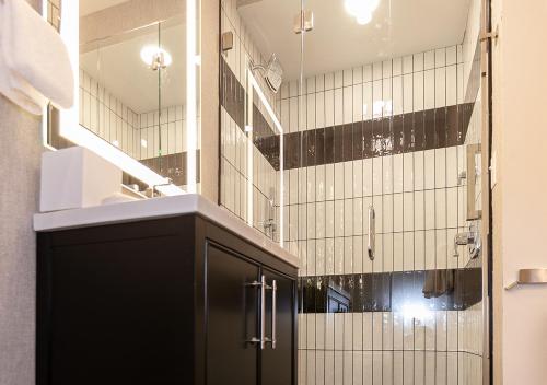 a bathroom with a black cabinet and black and white tiles at The Rubenstein Hotel in New Orleans