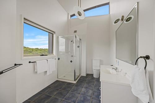 a white bathroom with a shower and a sink at Beach Escape Penthouse 2 Bdr Apartment in Sandy Point