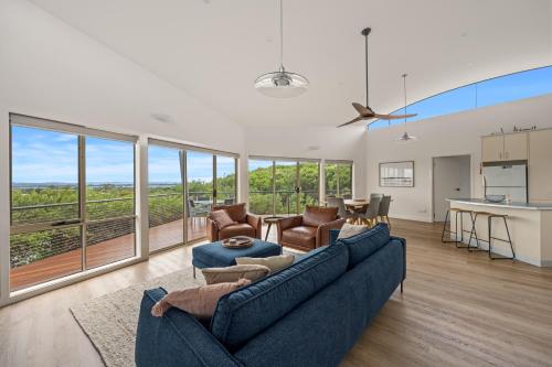 a living room with a blue couch and chairs and windows at Beach Escape Penthouse 2 Bdr Apartment in Sandy Point