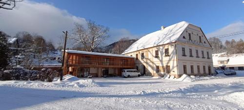 a large building with snow on the ground next to it at Apartment Ve Mlýně in Teplice nad Metují