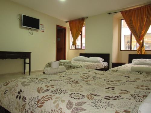 1 Schlafzimmer mit 2 Betten und einem Flachbild-TV in der Unterkunft HOTEL COLONIAL in Ipiales