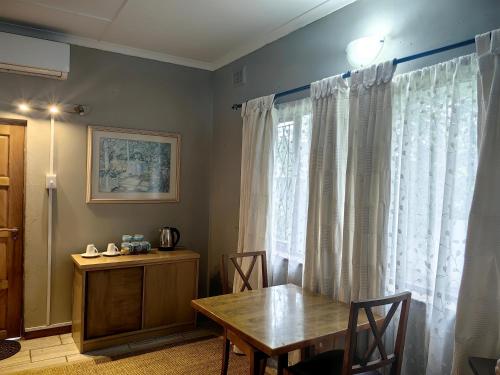 comedor con mesa y ventana en Mitchell Guesthouse, en Pietermaritzburg