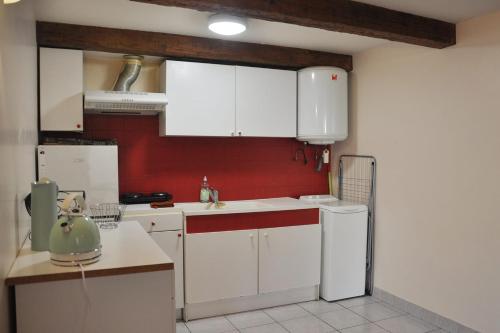une cuisine avec des placards blancs et un mur rouge dans l'établissement Cozy 1-Bedroom Apartment near Vieux-Port, à Marseille