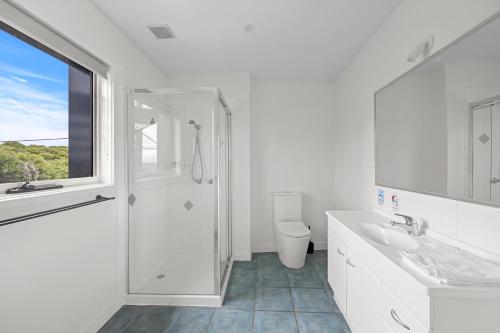 a white bathroom with a shower and a sink at Sandy Point Beach Escape 1 Bedroom Apartment in Sandy Point