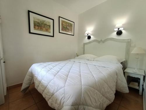 LOCATION 4 personnes GOLF DE PONT ROYAL EN PROVENCE في مالمور: غرفة نوم بسرير ابيض مع وجود صورتين على الحائط