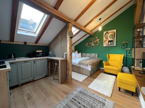 sypialnia z zielonymi ścianami, łóżkiem i żółtym krzesłem w obiekcie Studio Rezistenta w Fogaraszu