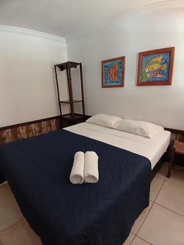 a bedroom with a bed with two towels on it at Pousada das Palmeiras in Garopaba