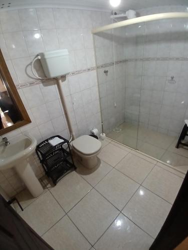 a bathroom with a shower and a toilet and a sink at Pousada das Palmeiras in Garopaba