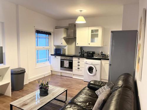 a living room with a couch and a kitchen at Yeovil Apartments in Yeovil