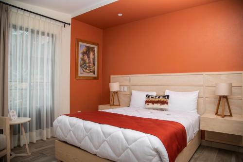 a bedroom with a large bed with an orange wall at Quinta Mercedes in Guanajuato