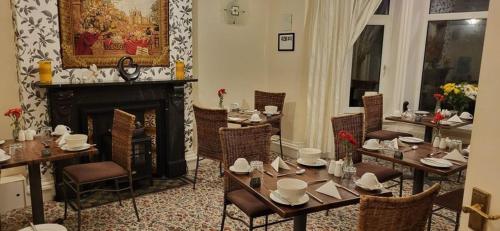 a dining room with tables and chairs and a fireplace at Ferndene Guest House in Keswick