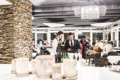 deux hommes assis à une table avec des bouteilles de vin dans l'établissement Boutique Hotel Riviera, à Spiez