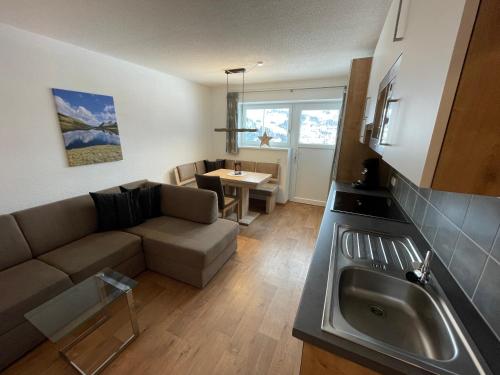 sala de estar con sofá y cocina con fregadero en Ferienwohnung Roschitz en Schruns-Tschagguns