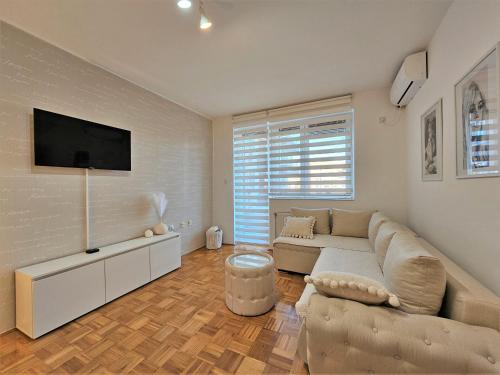 ein Wohnzimmer mit einem Sofa und einem Flachbild-TV in der Unterkunft Apartman Elle in Sombor