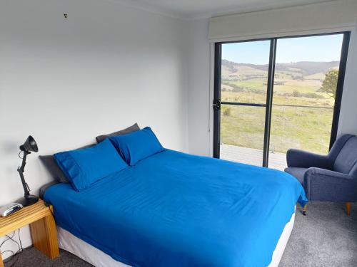 a bedroom with a bed and a chair and a window at Fingerpost Hill Farm Stay in Campania