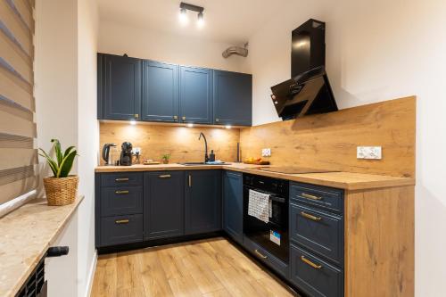 eine Küche mit marineblauen Schränken und Holzböden in der Unterkunft Apartament Fika - klimatyczny w centrum miasta by SpaceApart in Jelenia Góra