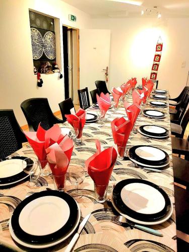 un lungo tavolo con sedie e piatti rossi e bicchieri da vino di L'auberge Angevine ad Angers