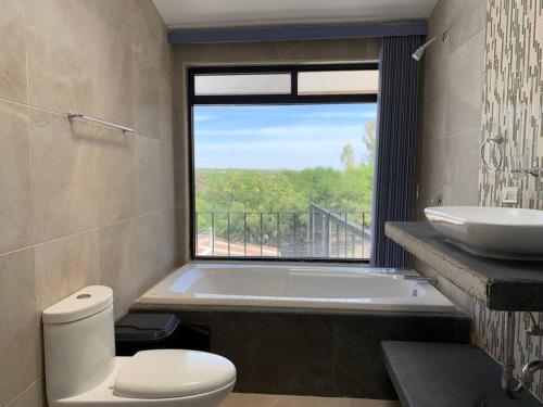 La salle de bains est pourvue d'une baignoire, de toilettes et d'une fenêtre. dans l'établissement Villa privada con una vista espectacular!, à Aguascalientes