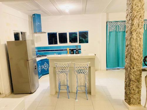 eine Küche mit einem Kühlschrank und 2 Barhockern in der Unterkunft Hermosa cabaña privada cerca a Tulua con jacuzzi 