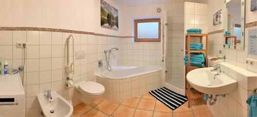a bathroom with a toilet and a sink and a tub at Ferienwohnung Am Wundergraben inkl. Chiemgaukarte in Ruhpolding