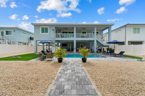 a home with a swimming pool and a house at Mermaid's Paradise ~ Pool ~ Dock ~ Games ~ Views in Marathon