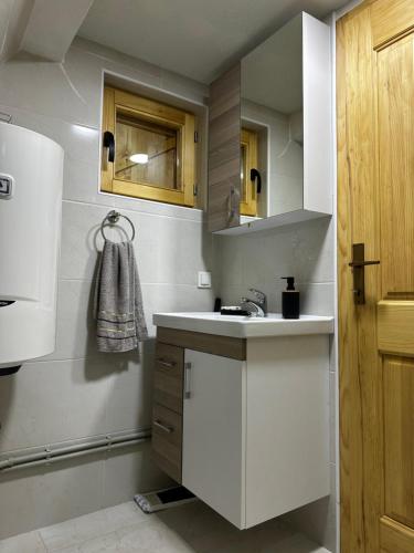 eine weiße Küche mit einer Spüle und einem Kühlschrank in der Unterkunft Vila Durmitorska bajka in Žabljak